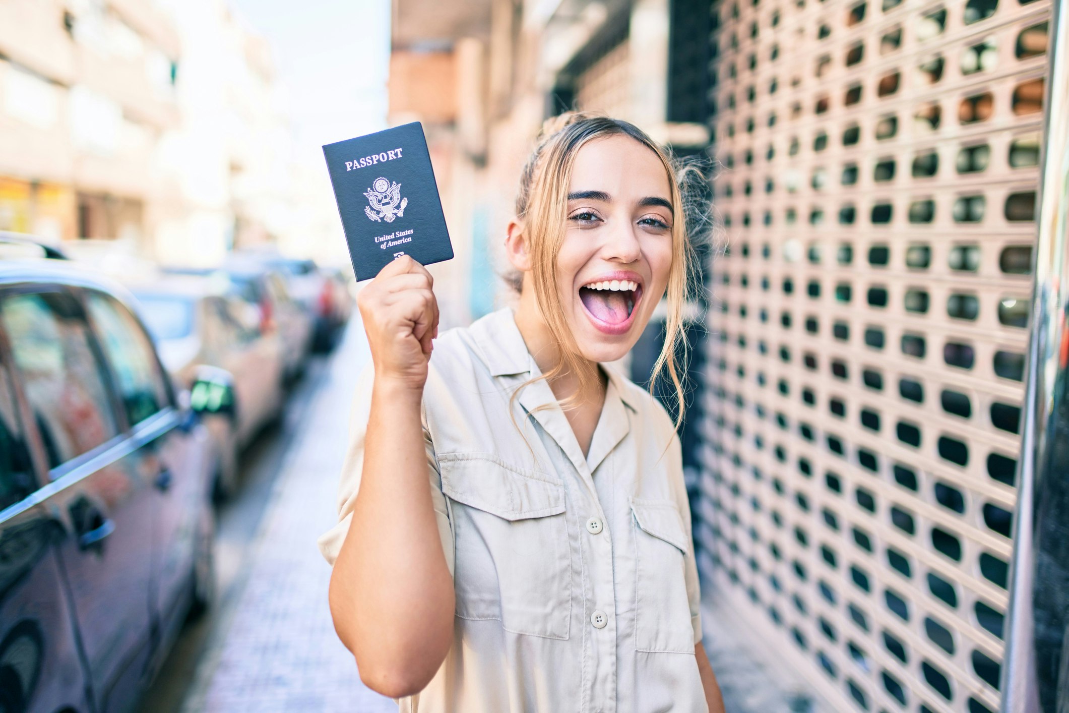 Young beautiful blonde caucasian woman smiling happy outdoors on a sunny day showing USA passport